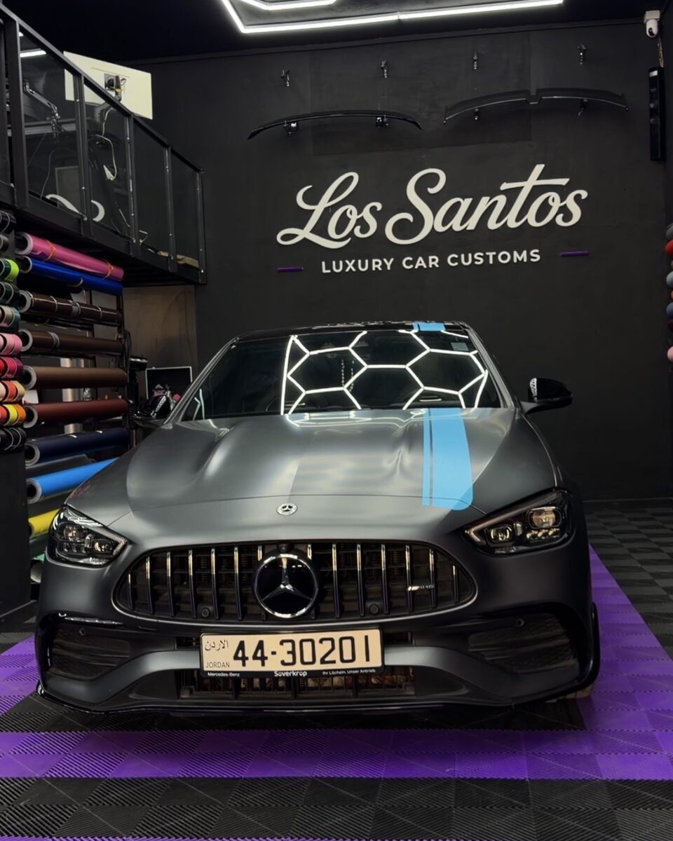 Front view of a Mercedes AMG C43 with matte sky blue racing lines inside the Los Santos studio