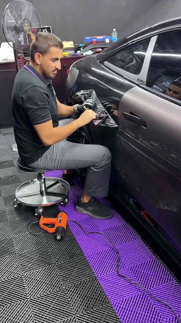 A technician applying vinyl around a car body