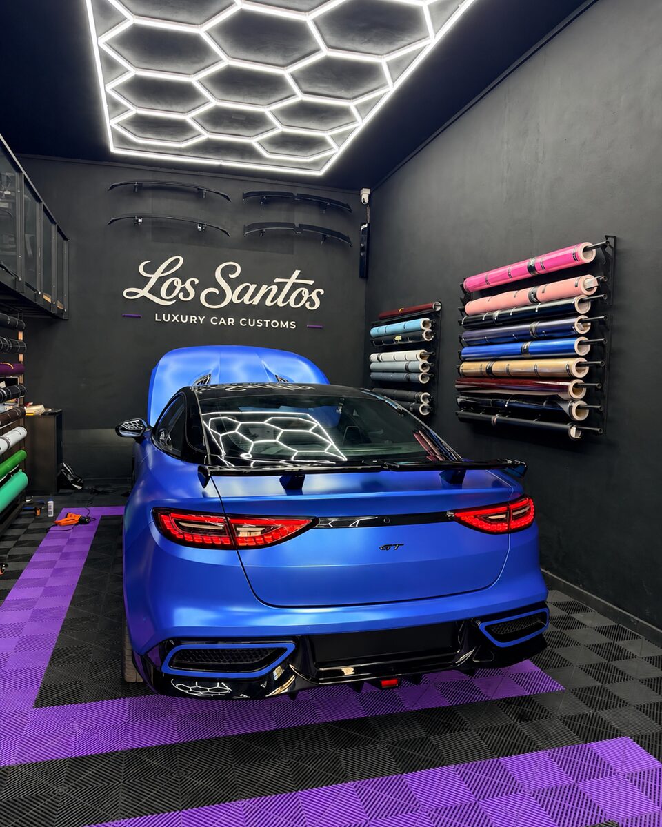 Rear view of a Neta GT with an electro metallic satin ocean blue full color change inside the Los Santos studio